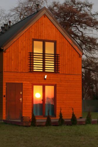 an orange house with a sunset in the window at Osada Natura in Śliwin
