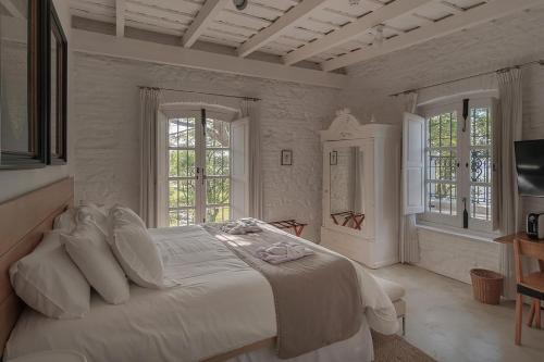1 dormitorio blanco con 1 cama grande y 2 ventanas en Charco Hotel, en Colonia del Sacramento
