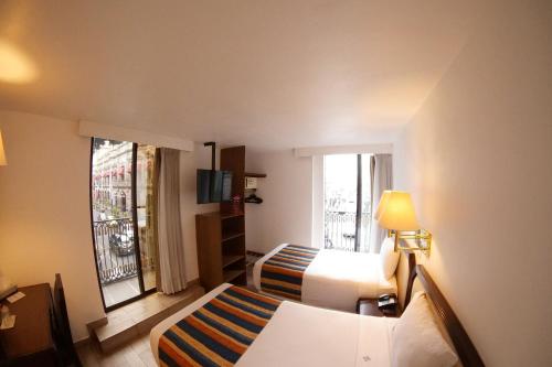 um pequeno quarto de hotel com uma cama e uma janela em Hotel Del Portal, Puebla em Puebla