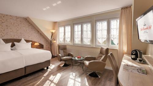 ein Hotelzimmer mit einem Bett, einem Tisch und Stühlen in der Unterkunft Der Romantik-Hof Greetsiel in Greetsiel