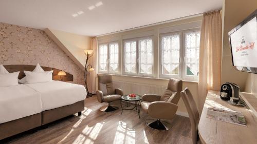 ein Hotelzimmer mit einem Bett und einem Tisch und Stühlen in der Unterkunft Der Romantik-Hof Greetsiel in Greetsiel