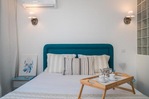 een bed met een blauw hoofdeinde en een houten tafel bij Serenity by the Marina, Vilamoura in Quarteira