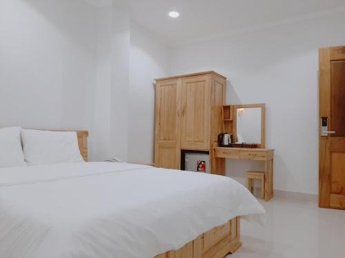 a bedroom with a white bed and a wooden cabinet at Minh Manh Hotel 2 in Pleiku