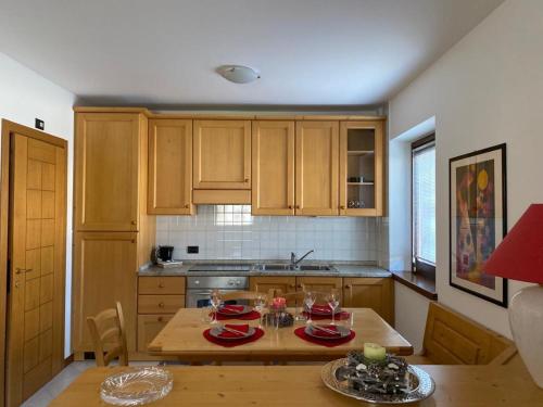 ヴァルディソットにあるCasa Bracchiのキッチン(木製のキャビネット、赤い食器を用意したテーブル付)