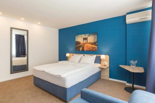 a hotel room with a bed and a blue wall at Premium Crown Suites in Belgrade