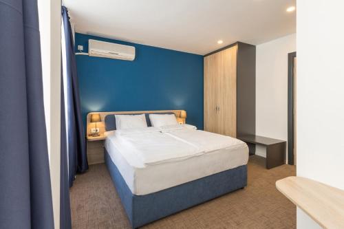 a bedroom with a large bed with a blue wall at Premium Crown Suites in Belgrade