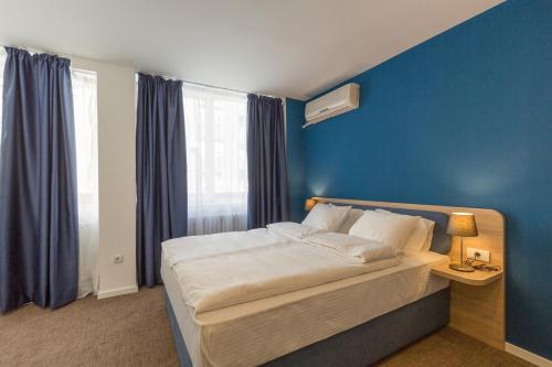 a bedroom with a bed with a blue wall at Premium Crown Suites in Belgrade
