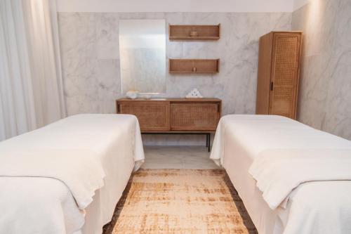 two beds in a room with a vanity and a mirror at Praia do Sal Resort in Alcochete