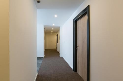 a hallway with white walls and a wooden door at Premium Crown Suites in Belgrade