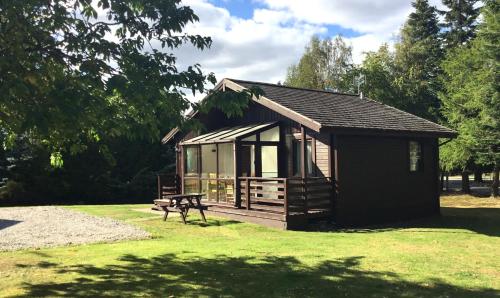 a small cabin with a bench in a park at Macdonald Spey Valley Resort in Aviemore