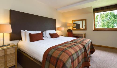 a hotel room with a large bed and a window at Macdonald Spey Valley Resort in Aviemore