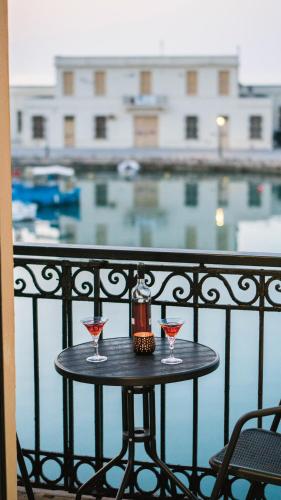 a table with two wine glasses on a balcony at Faros Rooms in Rethymno Town