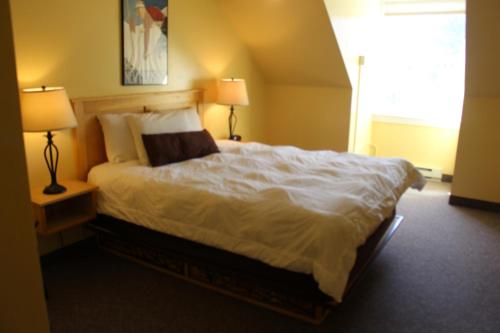 a bedroom with a large white bed with two lamps at Town Square Condominiums in Waterville Valley