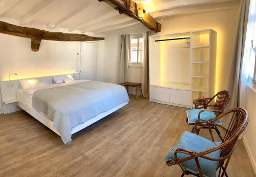a bedroom with a white bed and two chairs at Monschau-Auszeit: Historisch wohnen direkt am Bach in Monschau