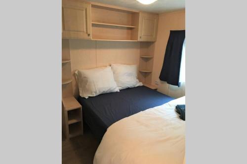 a small bedroom with a bed and white sheets at Heerlijke accommodatie op de Hoge Veluwe in Hoenderloo
