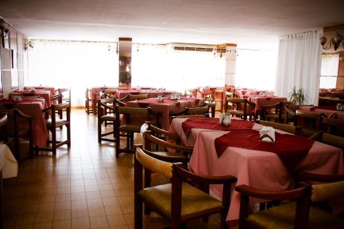 een restaurant met tafels en stoelen met rode tafellakens bij Hotel Menossi in Río Cuarto