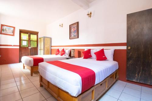 um quarto com 2 camas com lençóis vermelhos e brancos em OYO Hotel Meson de la Concepcion em Zacatecas