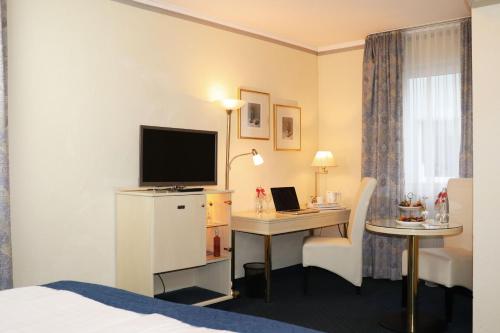 a hotel room with a desk with a television and a bed at Hotel Dalberg in Aschaffenburg