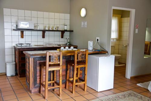 a kitchen with a counter with chairs and a refrigerator at Ikaia River Lodge in Keimoes