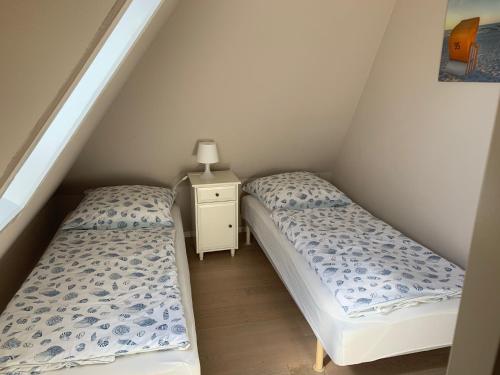 2 Einzelbetten in einem Dachzimmer mit einem Nachttisch in der Unterkunft Haus Kamp in Tinnum