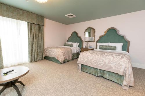 a bedroom with two beds and a table and a mirror at Mirbeau Inn & Spa, Rhinebeck in Rhinebeck