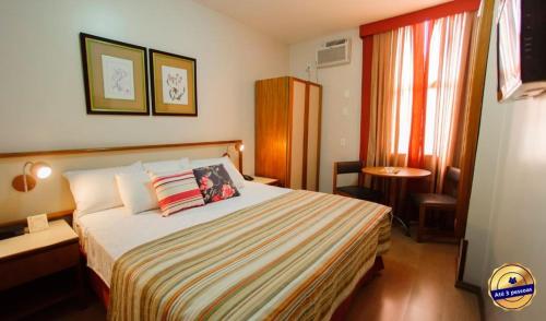een hotelkamer met een bed, een tafel en een raam bij César Inn Juiz de Fora Hotel in Juiz de Fora