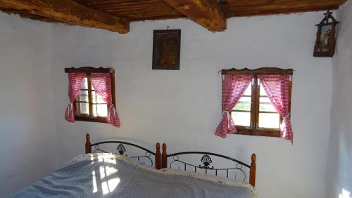 a bedroom with a bed and two windows at Homestay Kapl in Ledinek