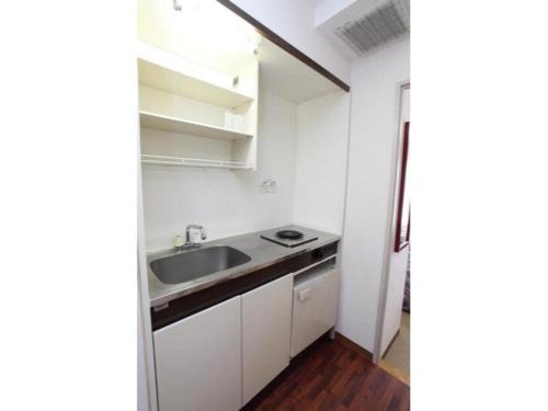 a kitchen with white cabinets and a sink at Sky Heart Hotel Kawasaki / Vacation STAY 80810 in Kawasaki