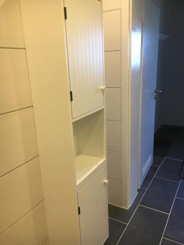 a closet with white cabinets and a tiled floor at Huck’s Ferienhäuser in Borstel