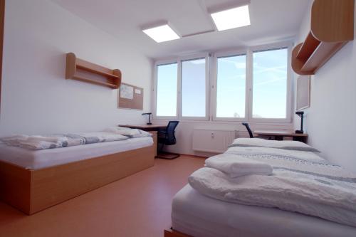 a room with three beds in a room with windows at Domov mládeže - Ubytování Sokolov in Sokolov