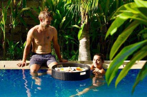 a man and a woman in a swimming pool at Jordan Guest House in Uluwatu
