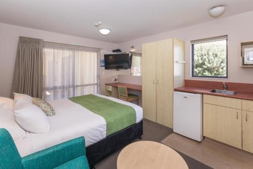 a small hotel room with a bed and a kitchen at Bella Vista Motel New Plymouth in New Plymouth