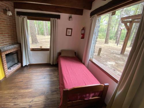 a room with a red bed in a room with two windows at Complejo de Cabañas Tunquelen in Mar de las Pampas