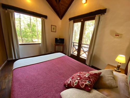 a bedroom with a large bed and two windows at Complejo de Cabañas Tunquelen in Mar de las Pampas