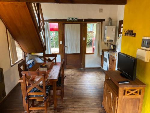a kitchen with a dining room table and a television at Complejo de Cabañas Tunquelen in Mar de las Pampas
