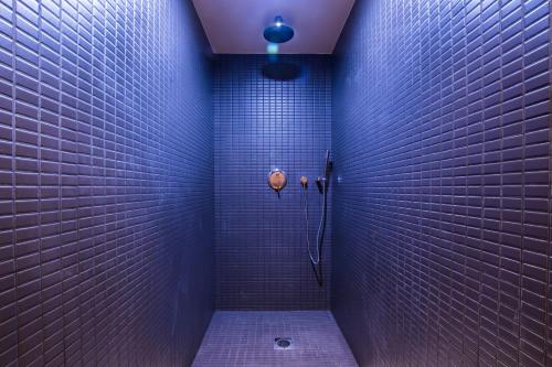 uma casa de banho com paredes em azulejo roxo e um chuveiro em Parasol Luxury Hotel & Suites Adults Only em Cárpatos