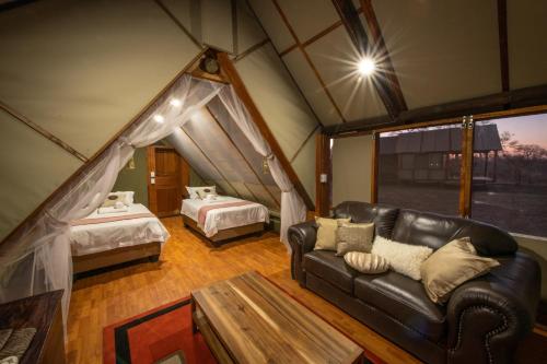 ein Wohnzimmer mit einem Ledersofa und ein Schlafzimmer in der Unterkunft Buffelshoek Tented Camp in Manyeleti Game Reserve