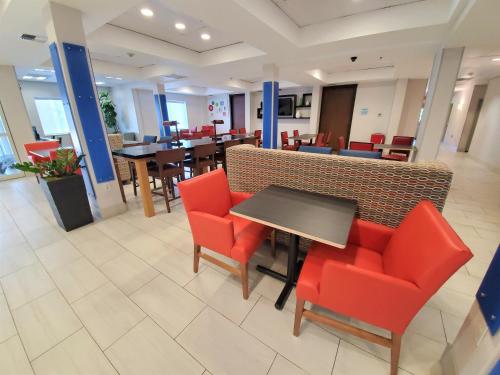 a restaurant with red chairs and a table and tables at Holiday Inn Express Hotel & Suites Seattle North - Lynnwood by IHG in Lynnwood