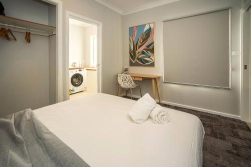 a bedroom with a large white bed with a chair at Kirsten Accommodation Parkes in Parkes