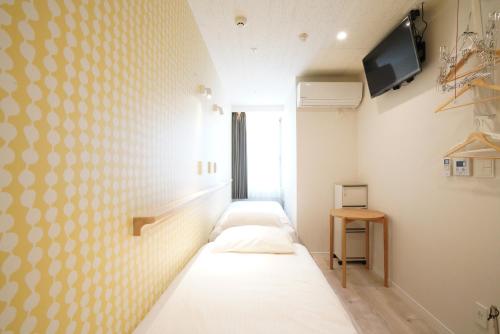 una camera con tre letti e una TV a parete di U-Hotel Takadanobaba a Tokyo