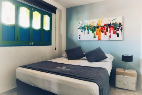 1 dormitorio con 1 cama y una pintura en la pared en La Martinera Parque Central, en Guatapé