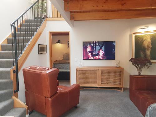 a living room with a staircase and a television at Villa 10 - Central Stylish Apartment in Queenstown