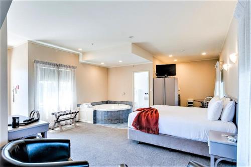 ヘイスティングズにあるCumberland Court Motelの大型ベッドとバスタブ付きのホテルルームです。
