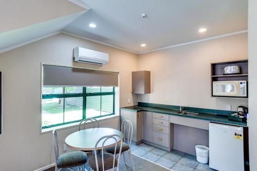 a kitchen with a table and a sink and a microwave at Cumberland Court Motel in Hastings