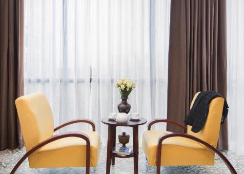 two chairs and a table with a vase of flowers at Siem Reap Palace Hotel & Spa in Siem Reap