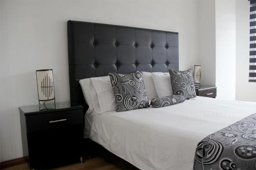 a bedroom with a large bed with a black headboard at Hotel Santafe Real in Bogotá