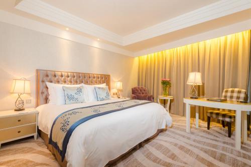 a bedroom with a large bed and a desk at Gubei Garden Hotel Shanghai Hongqiao in Shanghai