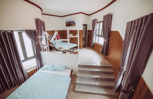 a room with a staircase with a bed and windows at ngaunhien's house - Homestay in Thôn Dư Khánh