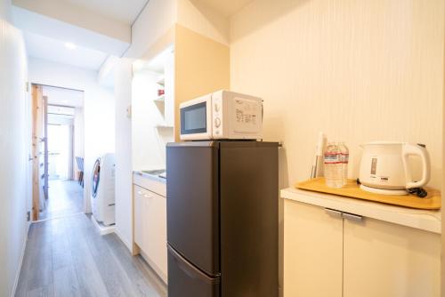 a kitchen with a microwave on top of a refrigerator at ZAITO Tokyo Kinshicho Economy Inn 宅东东京横川1民宿 in Tokyo