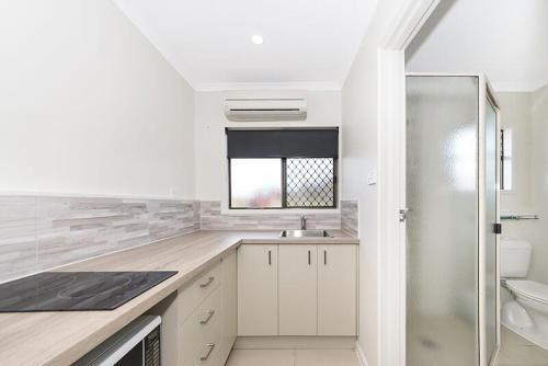 a white kitchen with a sink and a toilet at Cascade Motel In Townsville in Townsville